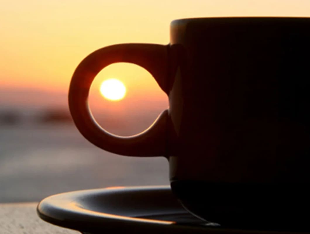 Coffee cup silhouette with setting sun in the background