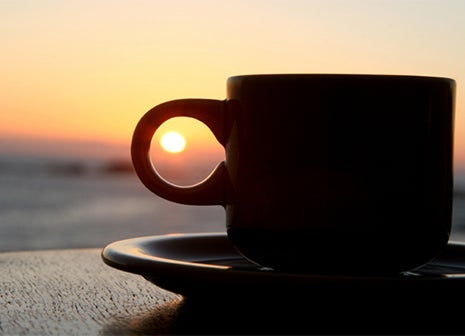 Coffee cup silhouette with setting sun in the background