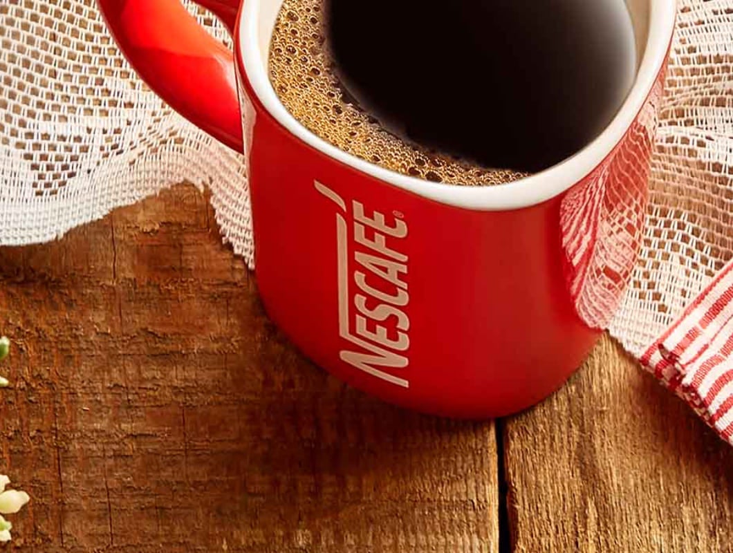 A red Nescafé mug on a table