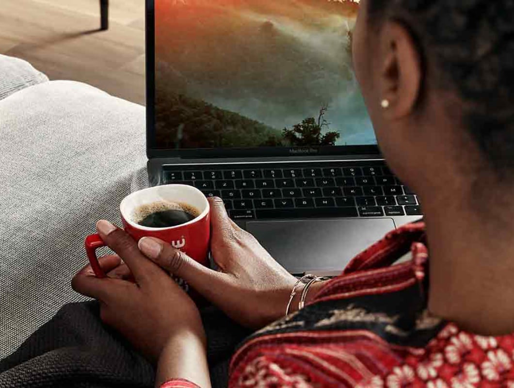 A woman looking at her laptop screen while on a sofa