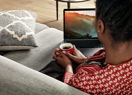 A woman looking at her laptop screen while on a sofa