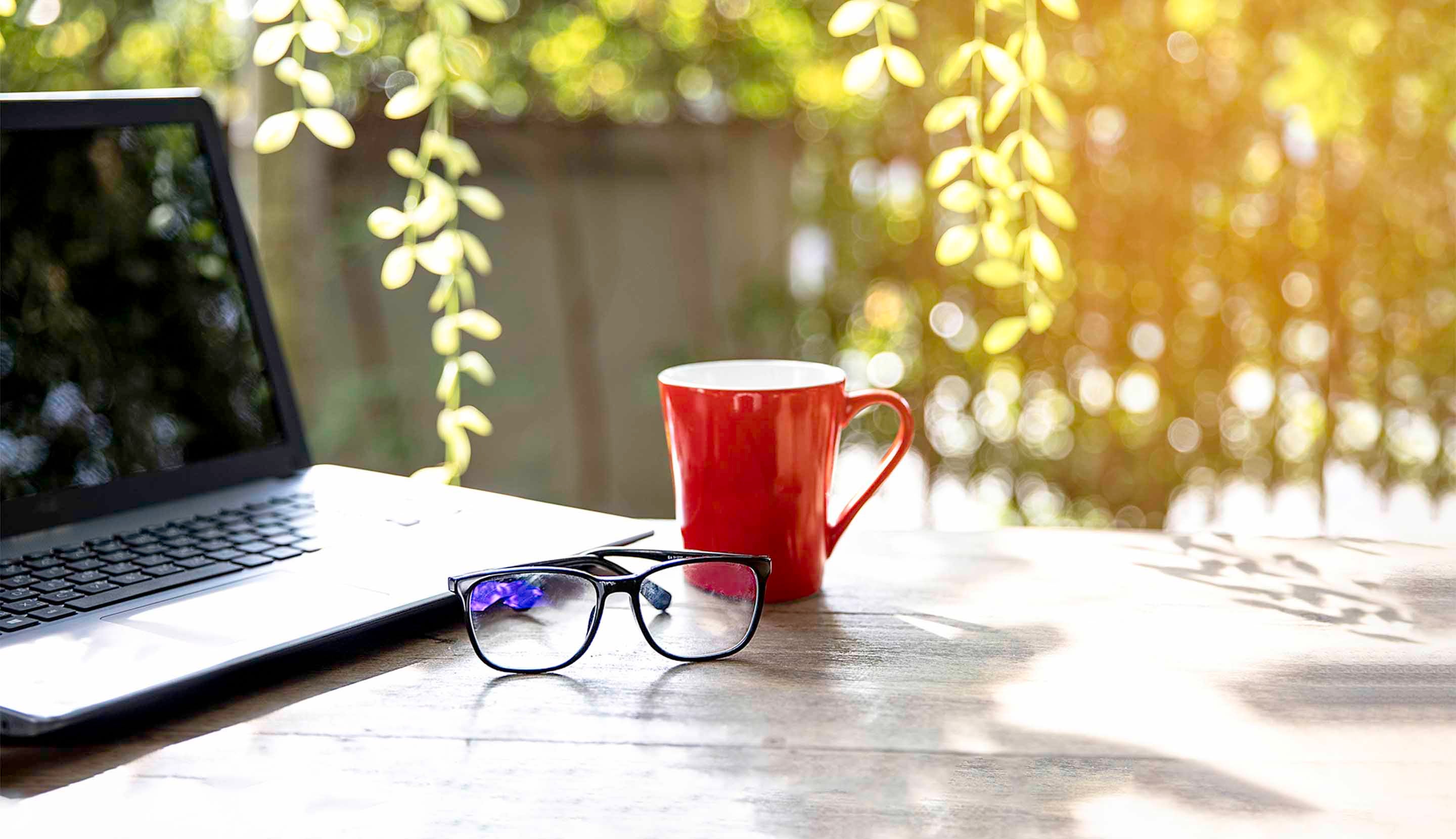 Cup coffee, glasses & laptop on table