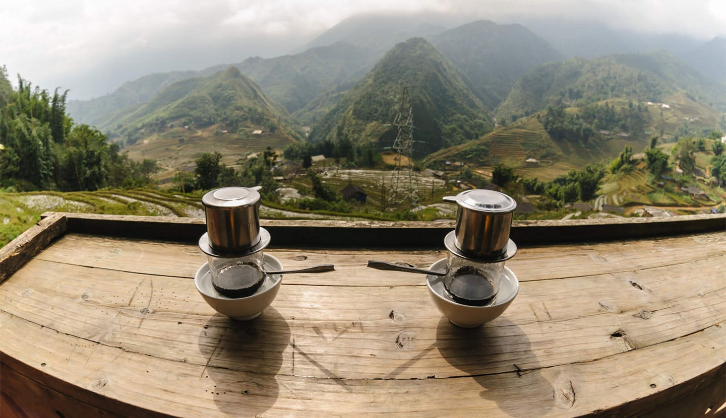Two Vietnamese coffees on a table overlooking a valley