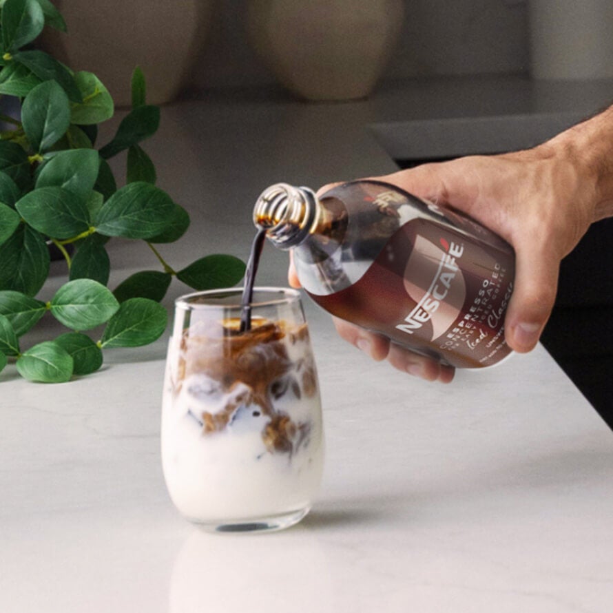 Pouring NESCAFÉ® Espresso Concentrate into a glass of ice and milk