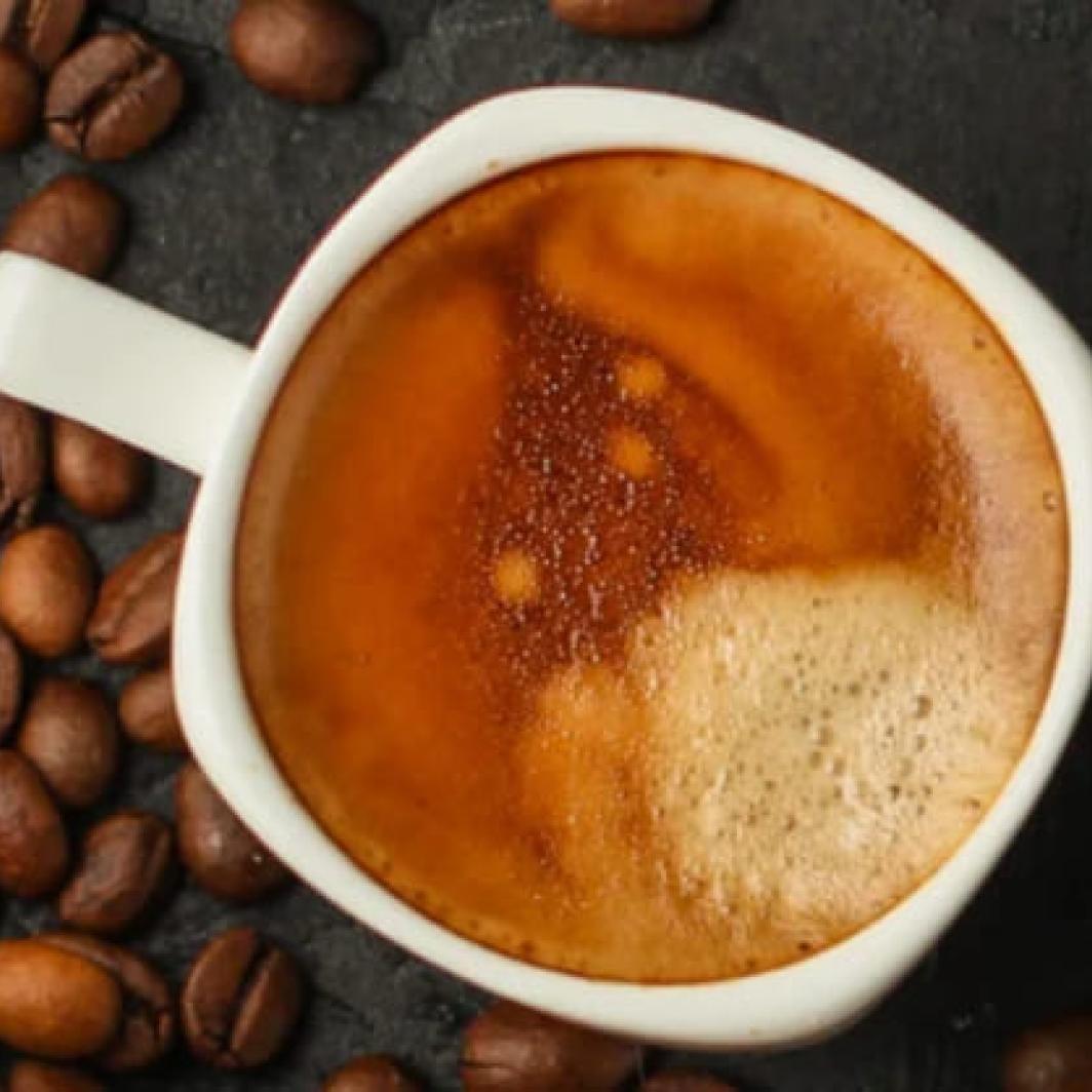 A top down shot of two coffees next to coffee beans