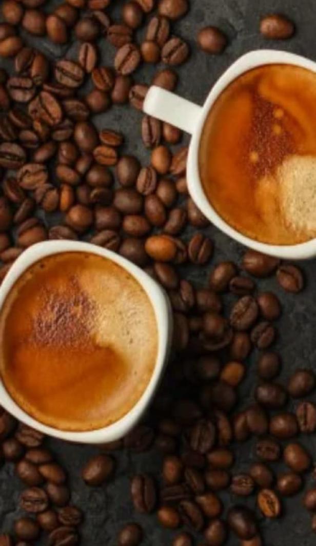 A top down shot of two coffees next to coffee beans