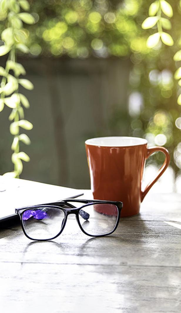 Cup coffee, glasses & laptop on table