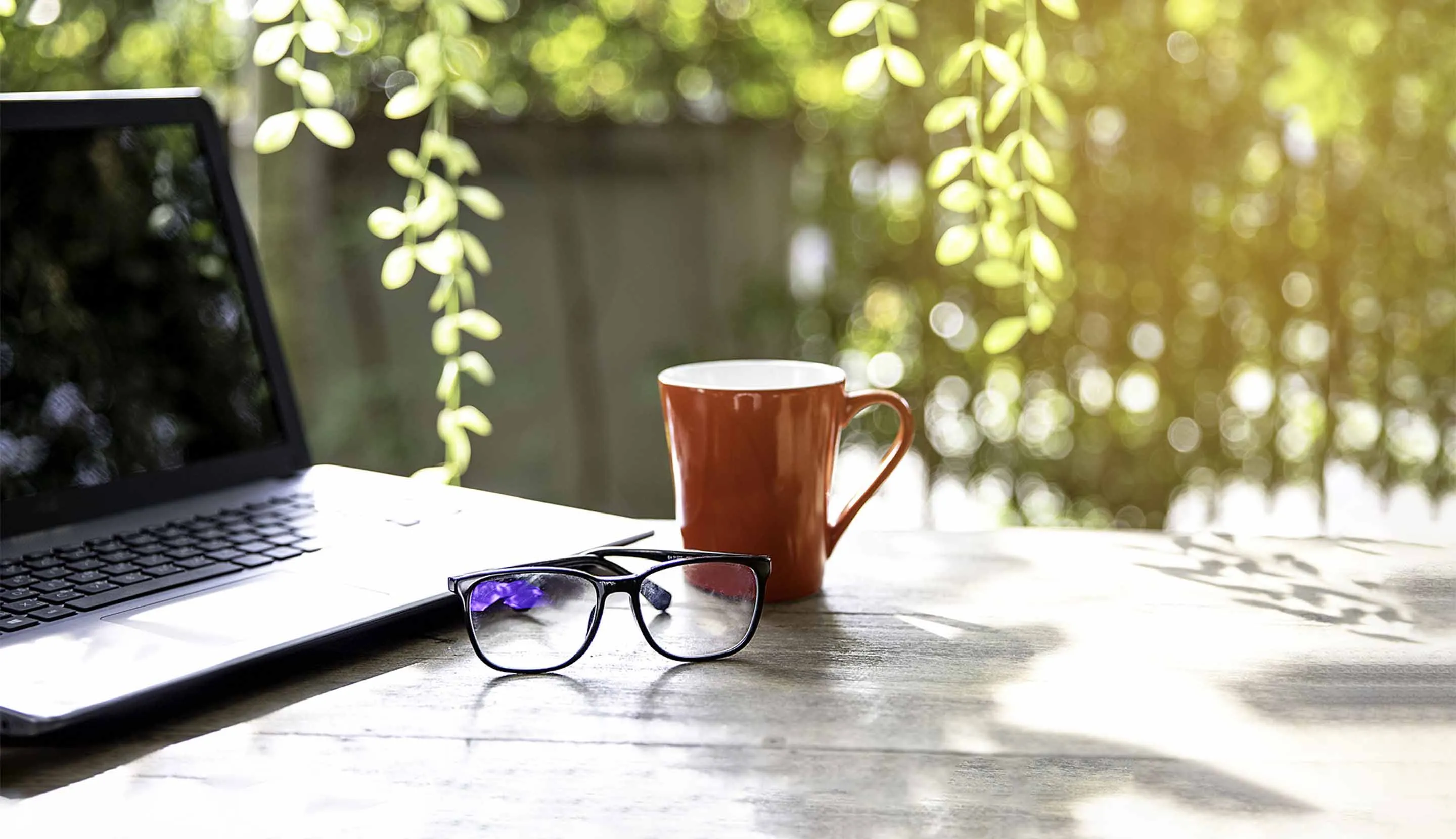 Cup coffee, glasses & laptop on table