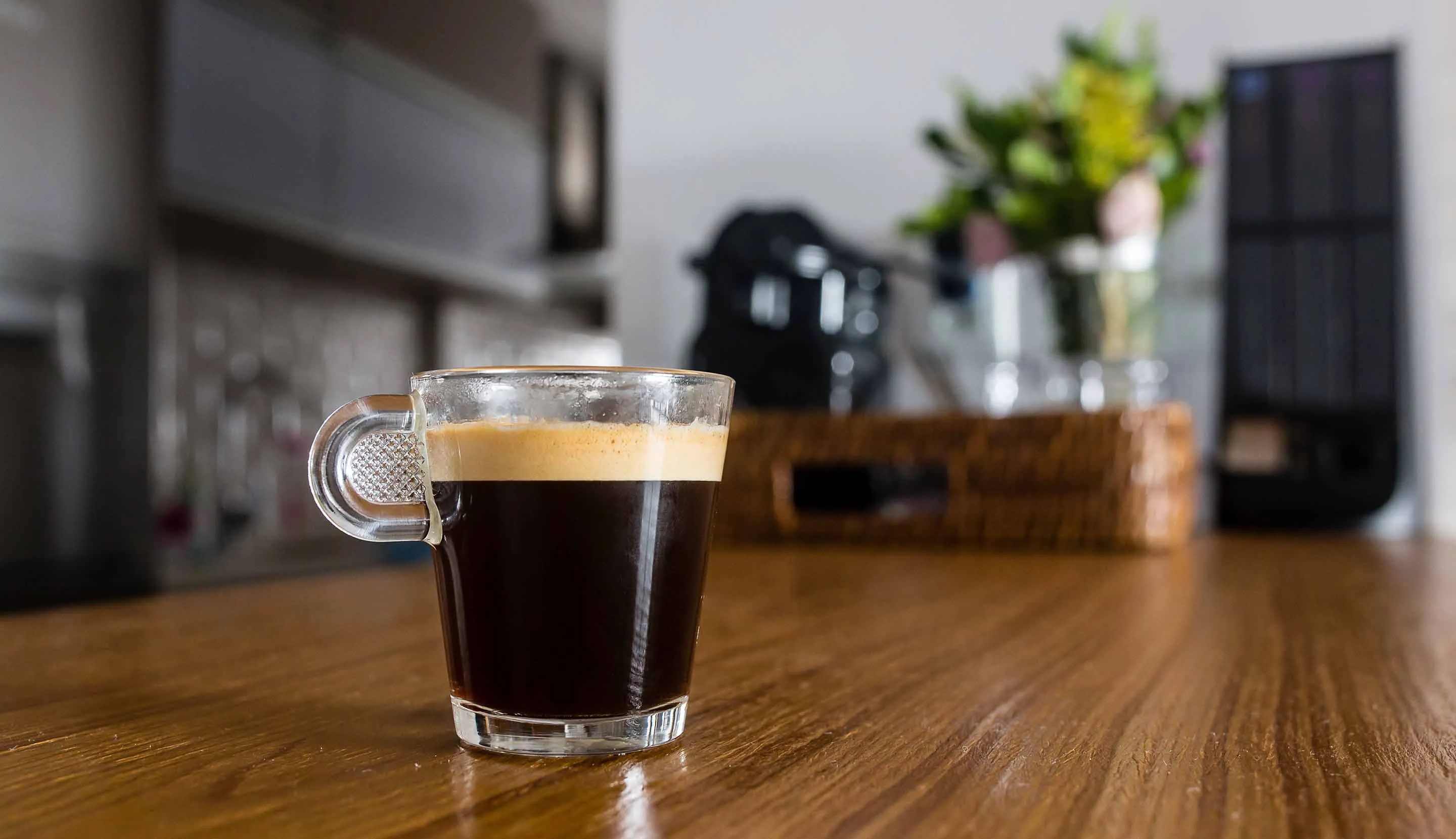 Freshly prepared black coffee in a glass cup on a kitchen table