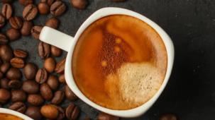 A top down shot of two coffees next to coffee beans