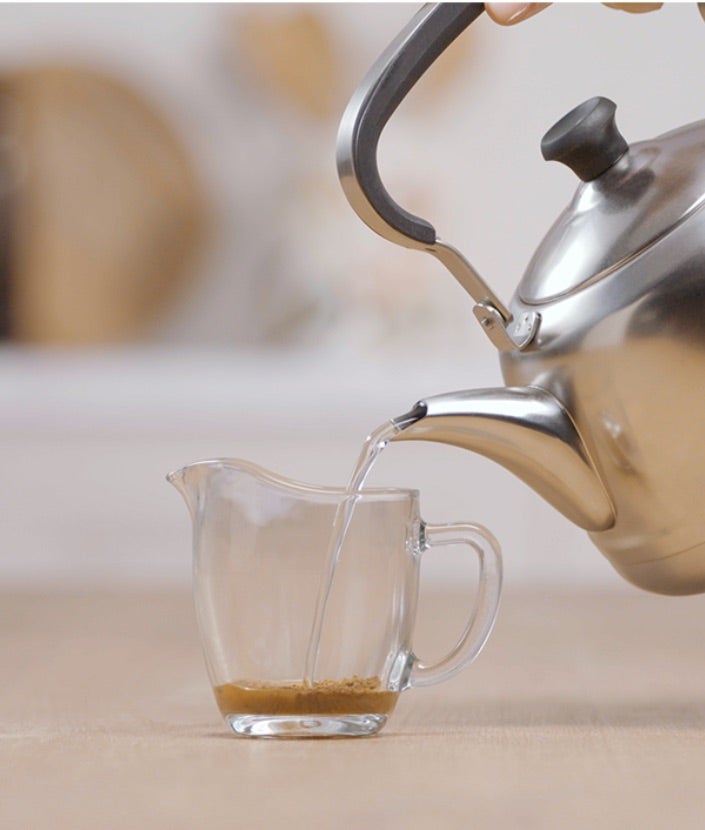 Dodavanje NESCAFÉ Gold kave, žličice zaslađivača i vruće vode u šalicu