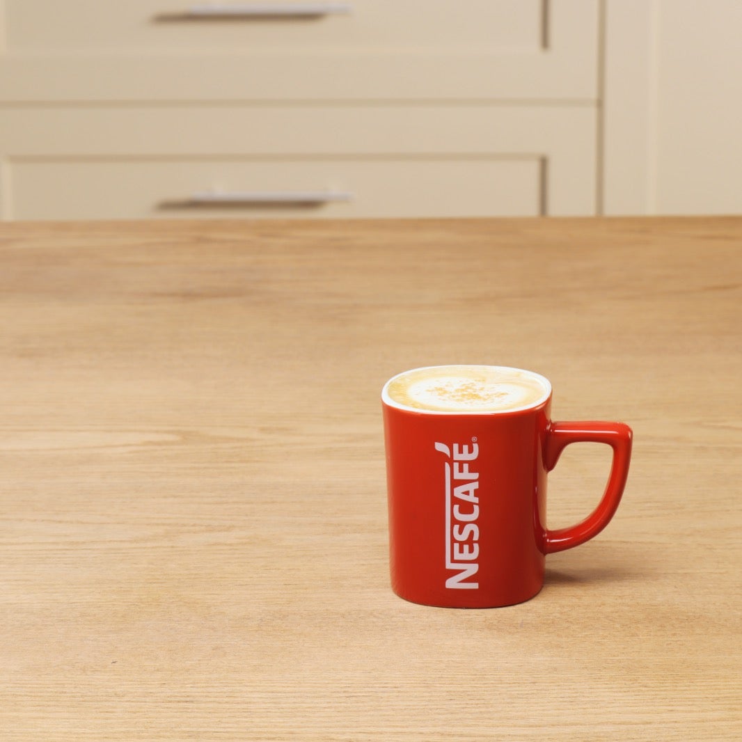 Vanilla Soy Latte kava sa sojinim napitkom u crvenoj Nescafé šalici na stolu