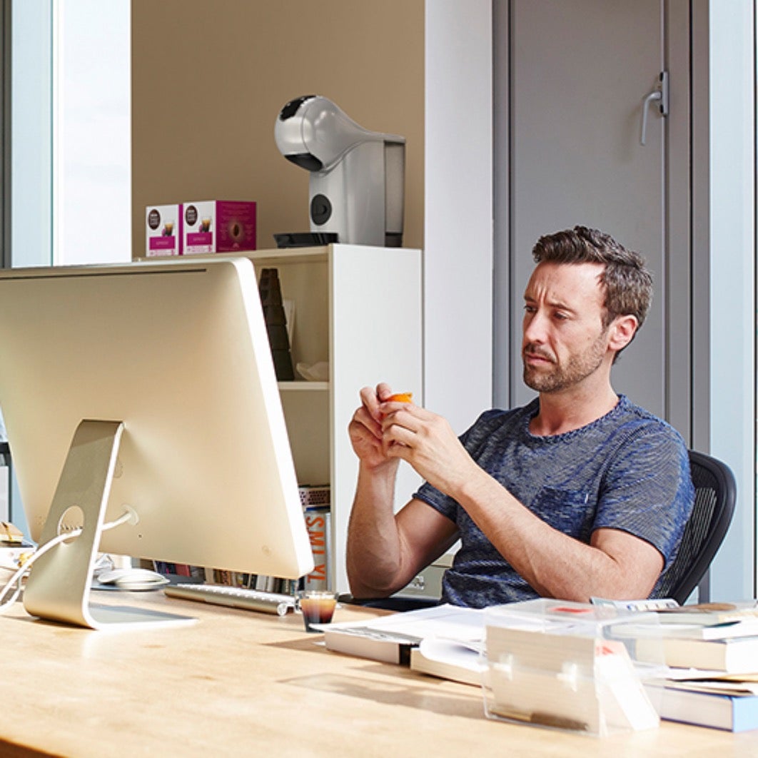 Muškarac sjedi ispred računala sa šalicom NESCAFÉ Dolce Gusto Espresso kave