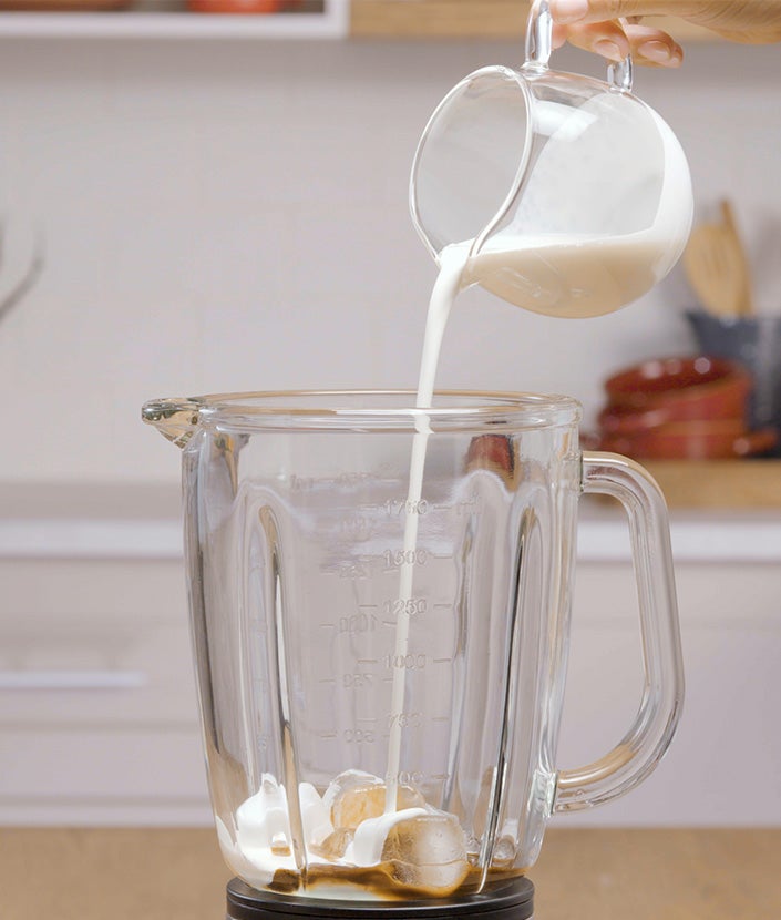 Ulijevanje zapjenjenog mlijeka u čašu s ledom