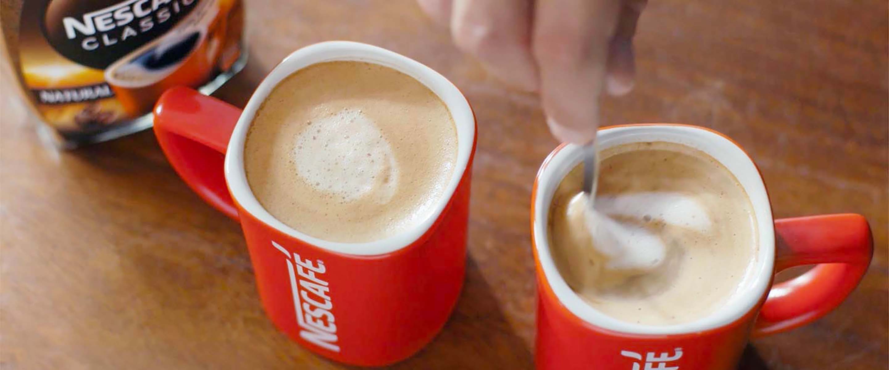 Dvije šalice ukusne i kremaste NESCAFÉ Classic kave su na stolu, spremne za posluživanje.
