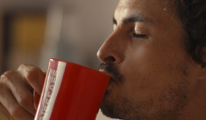 Muškarac uživa u kavi NESCAFÉ Classic s crvenom šalicom u ruci