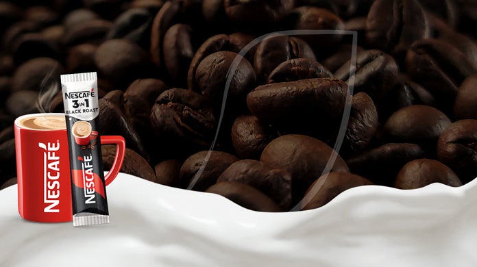 NESCAFÉ crvena šalica i NESCAFÉ 3in1 Black roast vrećica, na površini od zrna kave i mlijeka