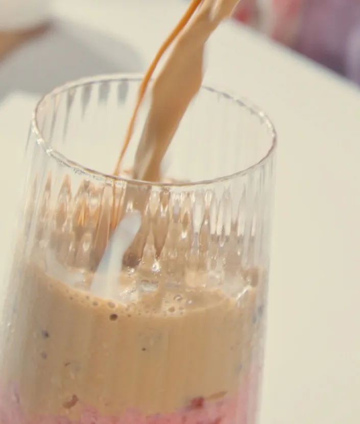 Pouring strawberry iced latte to a glass