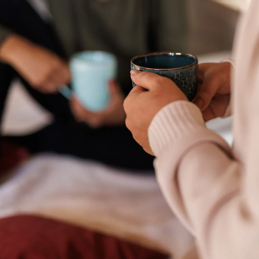 Vriendinnen die op de vloer zitten, koffie drinken en kletsen