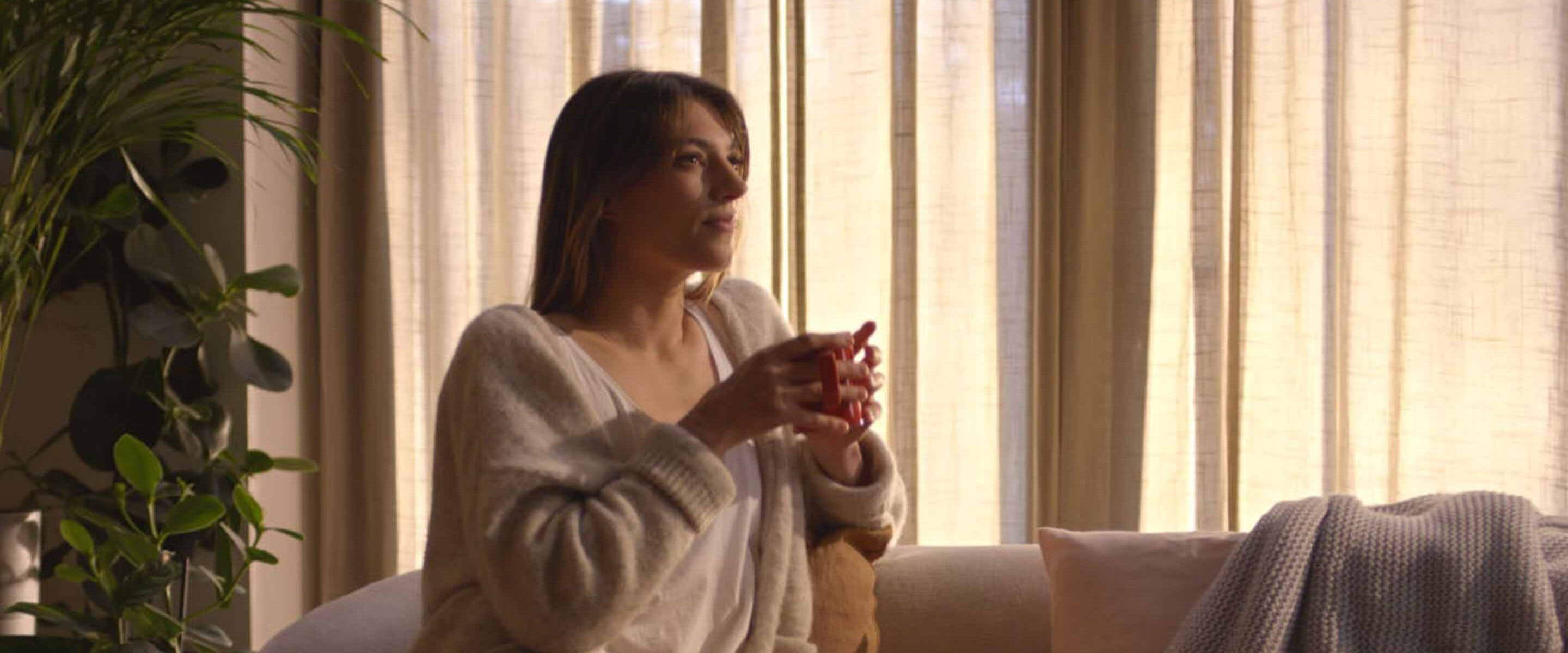 Kobieta siedząca na kanapie z kawą NESCAFÉ Crema