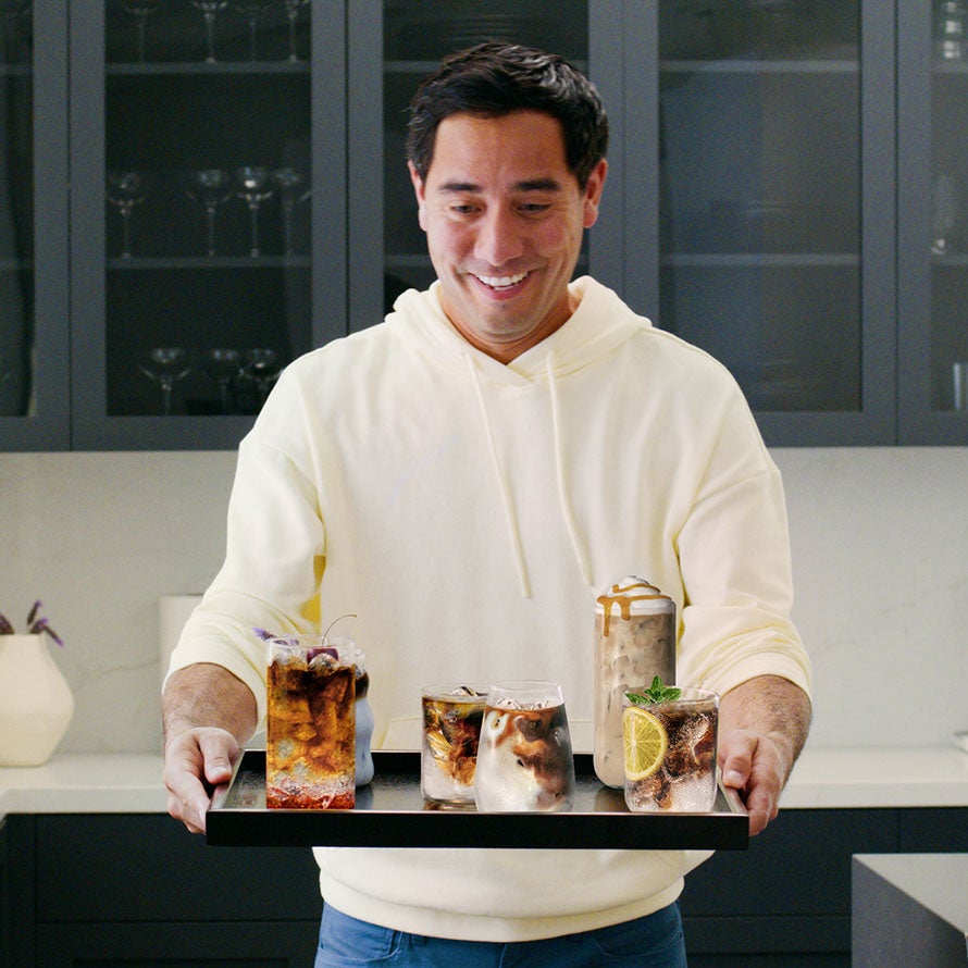 Zach King levando um tabuleiro com cafés frios