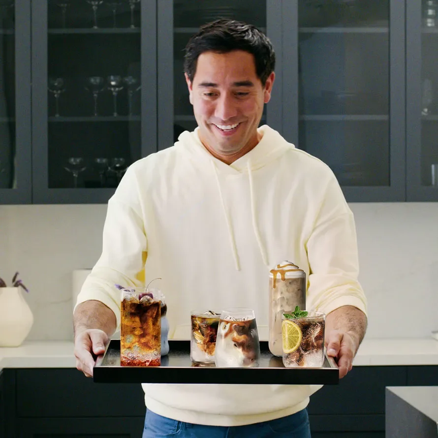 Zach King levando um tabuleiro com cafés frios