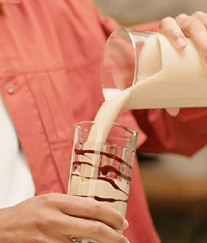 Barbat turnand bautura  NESCAFÉ Frappé Cappuccino Mocha intr-un pahar