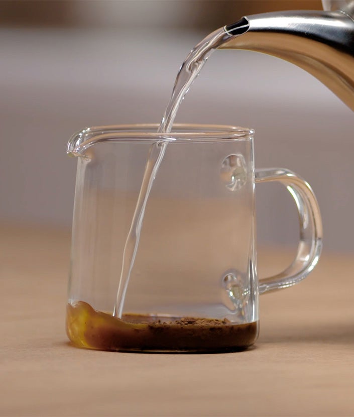 Sipanje vode u staklenu šolju sa kafom