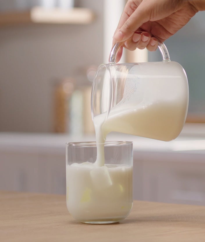Sipanje penjenog mleka u čašu sa kockicama leda