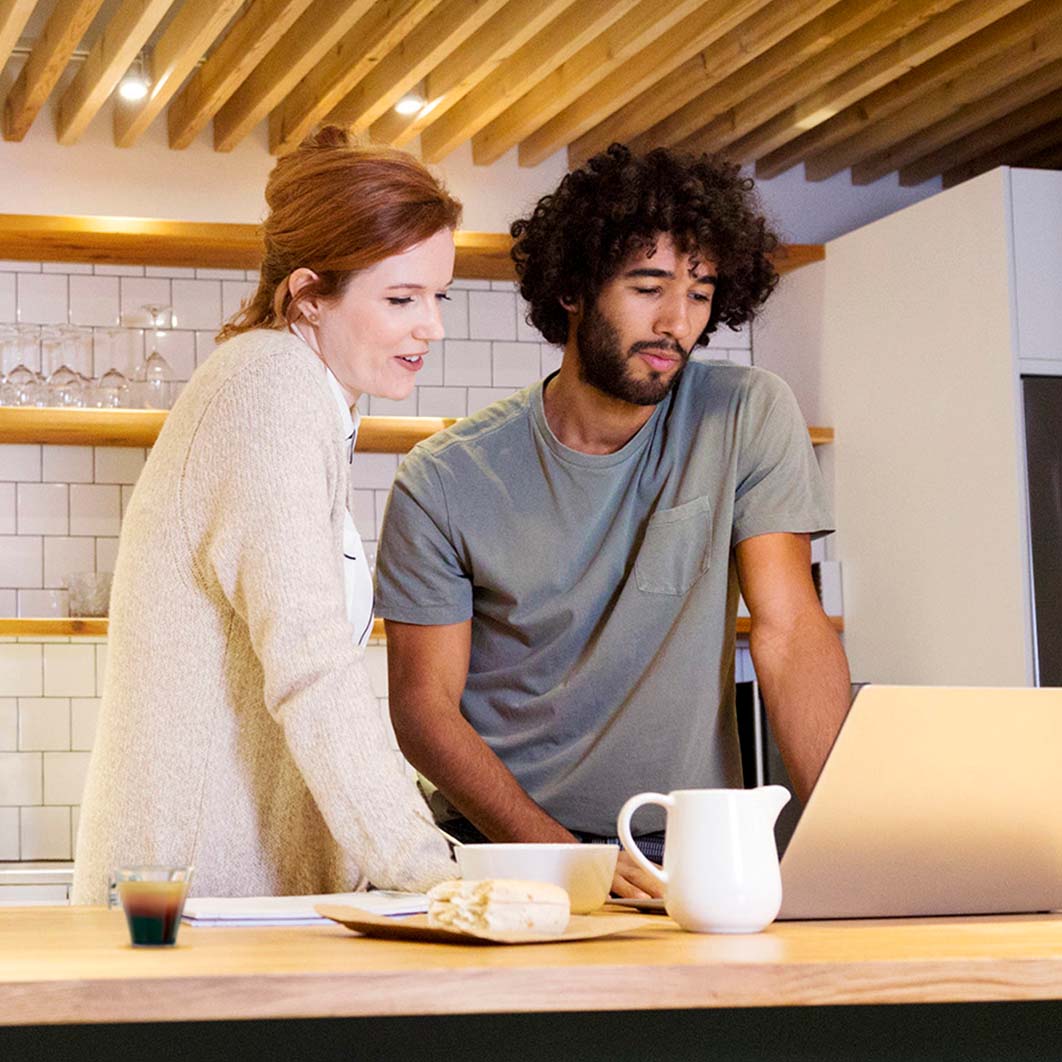 Muškarac i žena gledaju u tablet i pripremaju kafu na Dolce Gusto aparatu za kafu