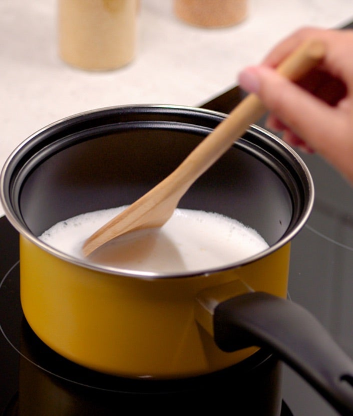 Zagrevanje mleka i bele čokolade u maloj posudi na šporetu