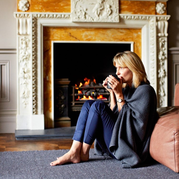 Žena sedi pored sofe i pije kafu