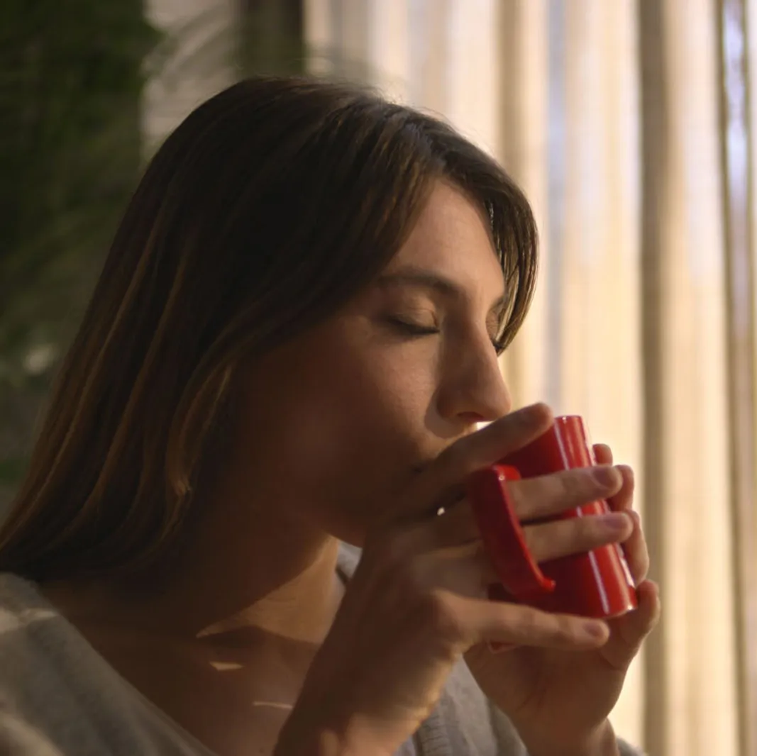 Žena pije NESCAFÉ Crema kafu