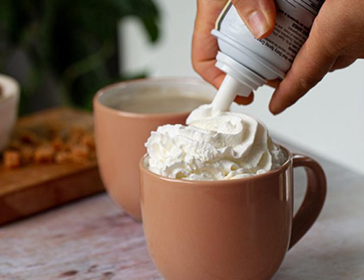 adding whipped cream onto cup