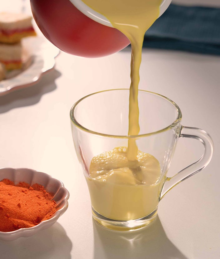 Pouring frothed milk into a coffee glass