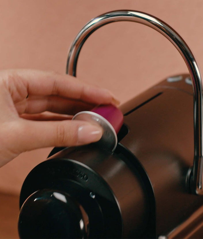 Adding coffee pod to Nespresso machine