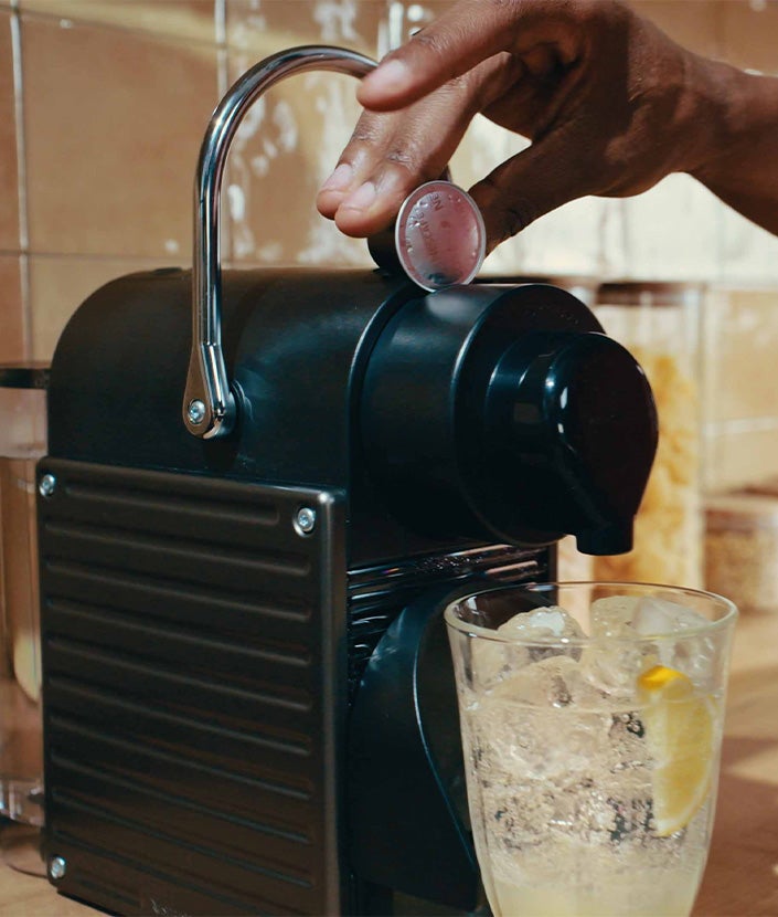 Hand placing Nespresso coffee pod into coffee machine