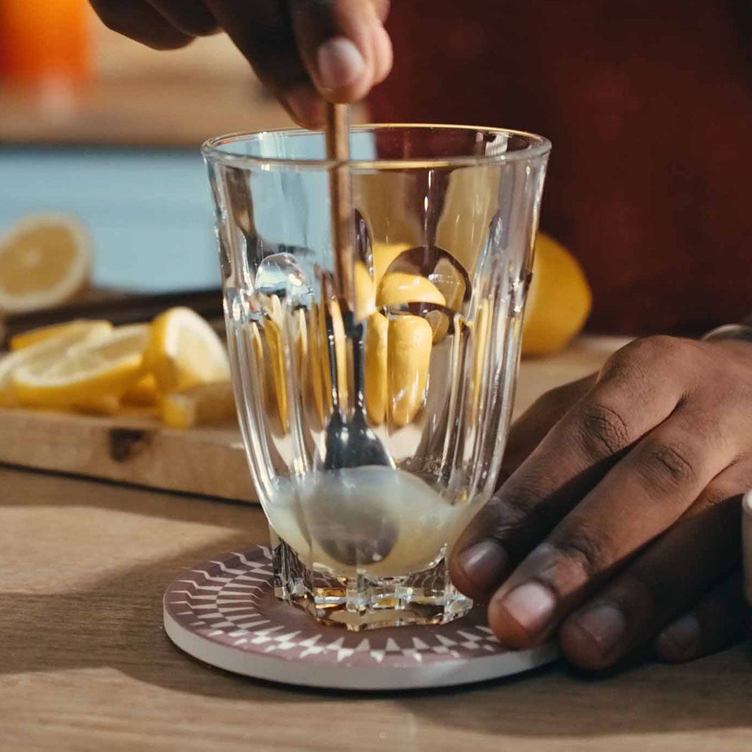 Hand stiring sugar into a coffee glass