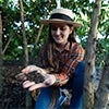 Woman examining healthy compost beneath shade trees caraousel image