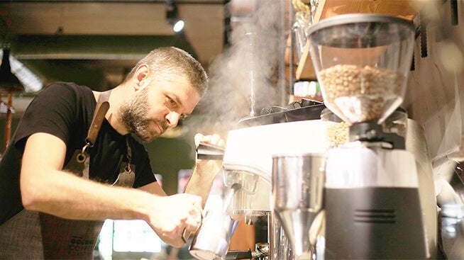 Barista steaming milk in a coffee shop