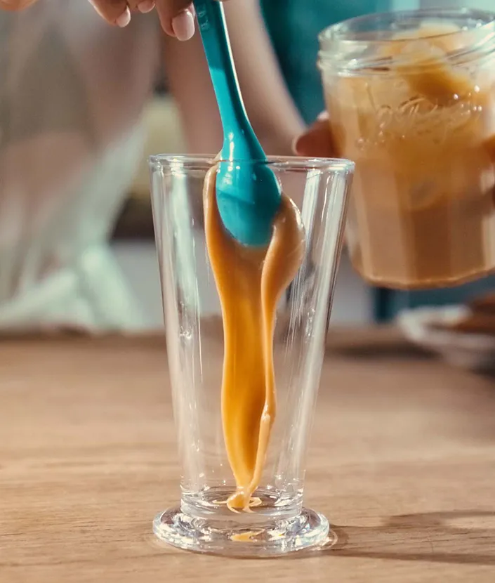 Hand adding dulce de leche to a tall glass