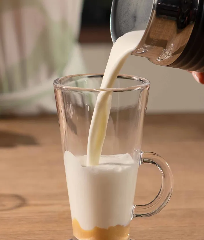 Pouring in froth milk into a tall latte glass