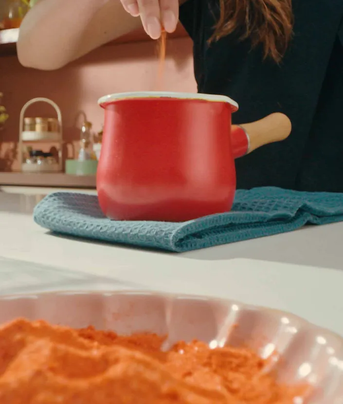 Hand stiring in saffron or turmeric into a pot of warmed milk 
