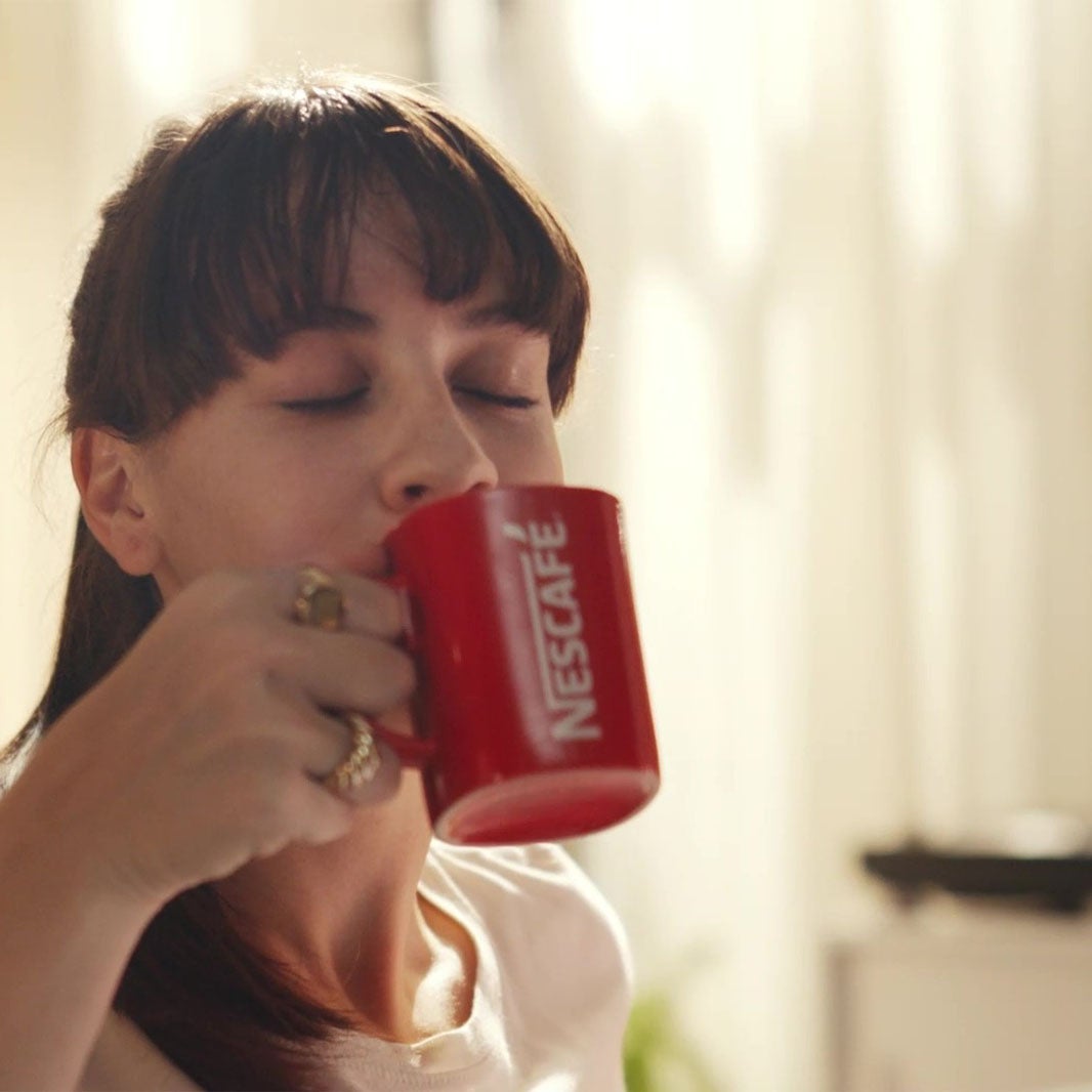 Dievča držiace šálku NESCAFÉ 3v1