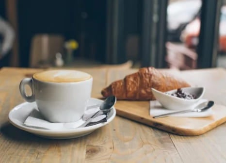 A cup of French coffee next to a croissant on a table