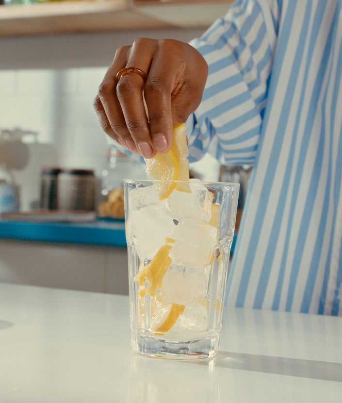 Adding ice cubes and lemon slice in a glass