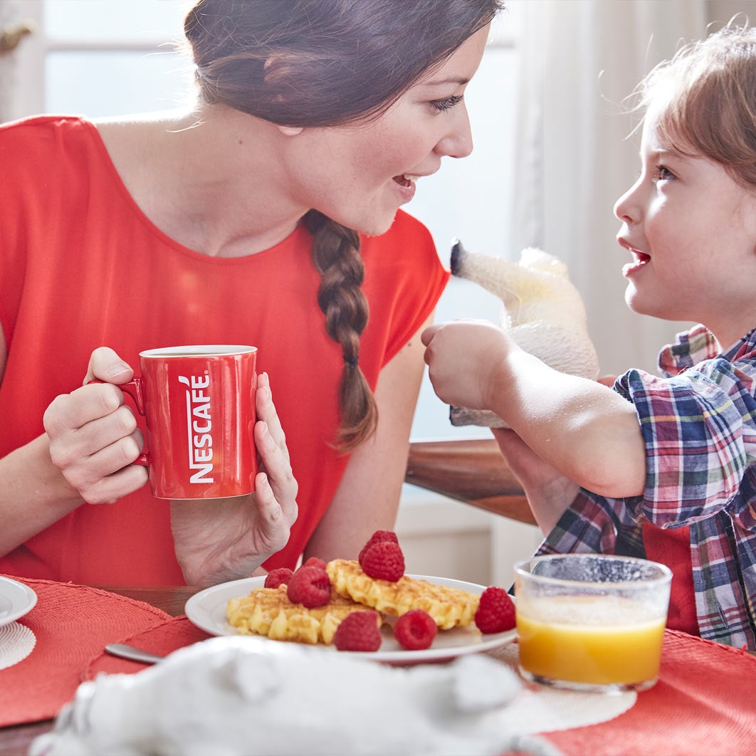 Genç kadın, Nescafé kupasındaki kahvesiyle kahvaltı yapıyor