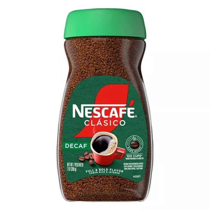 A jar of decaf Nescafé Clásico Dark Roast with a green cap, green "decaf" label and red coffee mug.