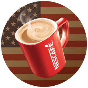 A red Nescafé mug filled with coffee on an American flag.