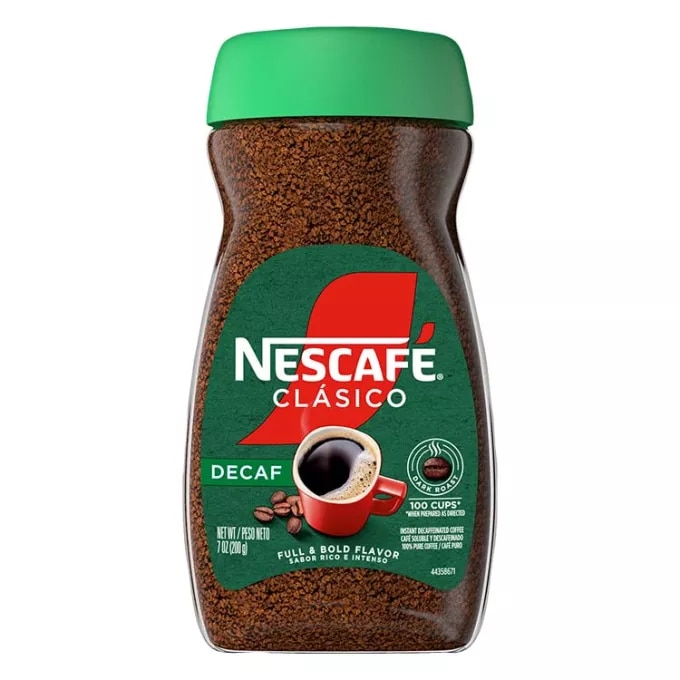 A jar of decaf Nescafé Clásico Dark Roast with a green cap, green "decaf" label and red coffee mug.